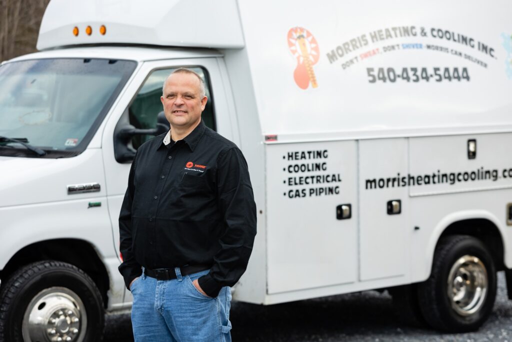 Morris, owner of Morris Heating & Cooling, standing in front of the company service truck